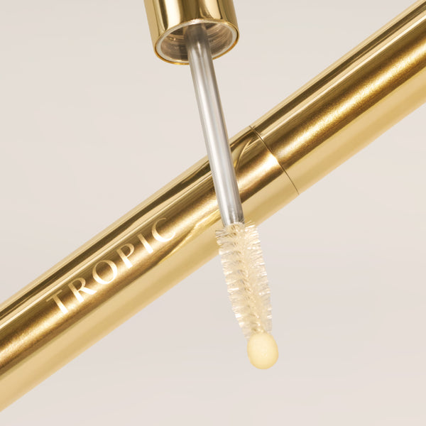 Close-up of the gold Lashful Eyelash Growth Serum showcasing its dual-ended applicator with a precision spoolie and soft cushion tip.