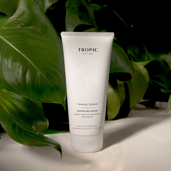 Tropic Tamanu Cream sensitive skin saviour displayed among lush green tropical leaves, highlighting its nourishing body care formula for sensitive skin.
