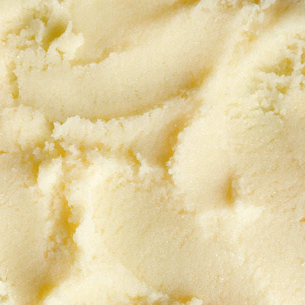 Close-up texture of creamy, whipped body scrub with a smooth, buttery consistency and soft sheen.