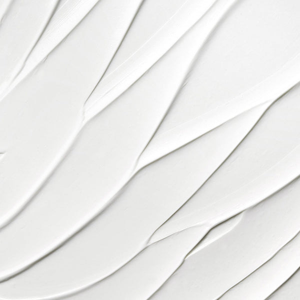 Close-up texture of smooth white cream with soft, sweeping ridges, showing a rich and velvety consistency.