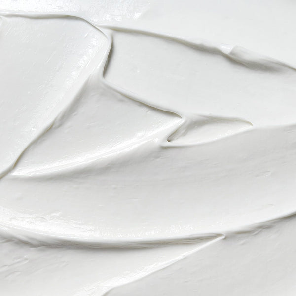 Close-up texture of Tropic Repairing Foot Remedy cream showing smooth, rich white moisturising formula spread across a surface.
