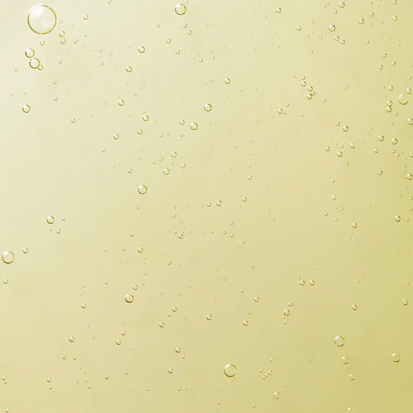 Close-up of a golden-yellow gel texture with small air bubbles, showing the smooth, cleansing consistency of Tropic’s Signature Hand Wash.