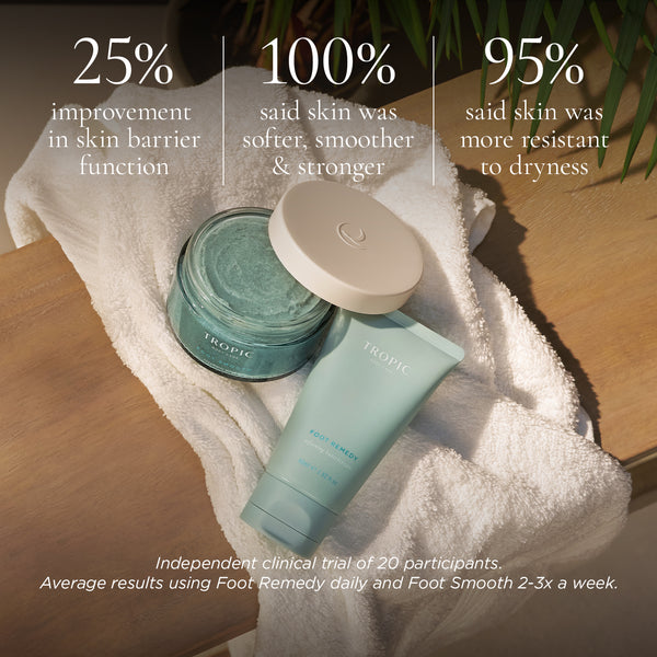 Tropic Foot Smooth Enzymatic Scrub and Foot Remedy Softening Buttercream displayed on a white towel with on-image clinical results highlighting improved skin barrier function, softer and smoother skin, and increased resistance to dryness.