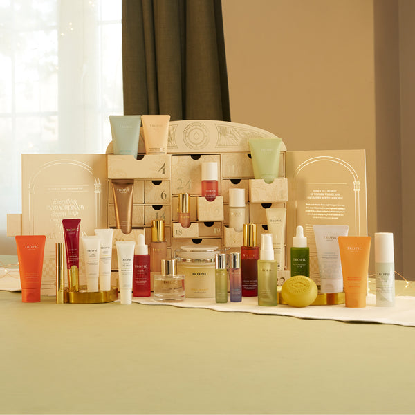 Tropic advent calendar open with 24 numbered drawers surrounded by all included skincare products displayed in front.