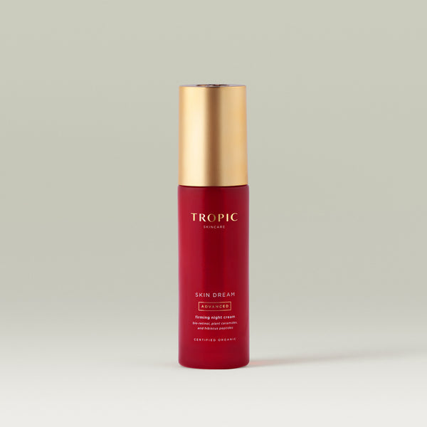 Tropic Skincare Skin Dream Advanced Firming Night Cream in a red bottle with a gold cap, on a neutral background.