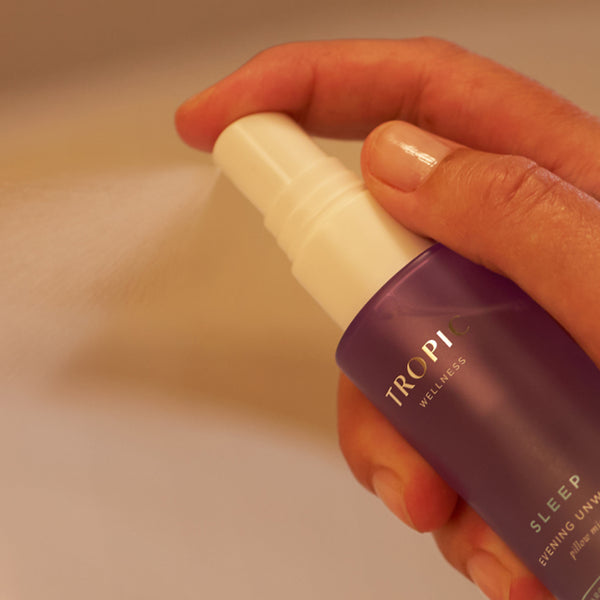 Hand holding Sleep Evening Unwind pillow mist spray bottle.