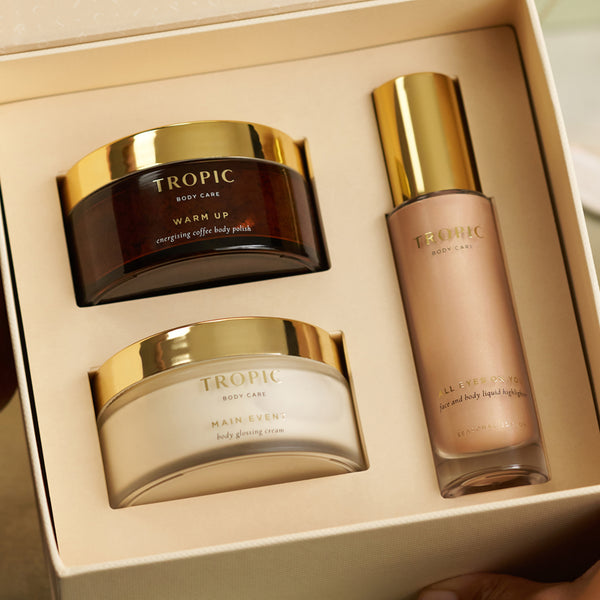 Tropic gift set open box with Warm Up Coffee Body Polish, Main Event Body Glossing Cream and All Eyes On You Liquid Highlighter.