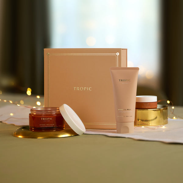 Tropic gift set with Ritual Release Warming Magnesium Polish, Mineral Milk and Deep Recovery Magnesium Balm beside blush pink gift box with fairy lights.