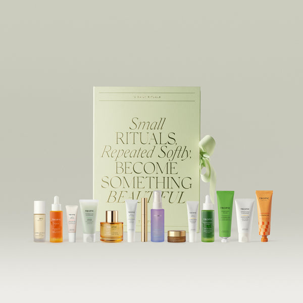 Tropic Skincare '12 Daily Rituals' gift set, featuring a sage green box reading 'Small Rituals, Repeated Softly, Become Something Beautiful', displayed with twelve skincare products including cleansers, serums, oils and creams.