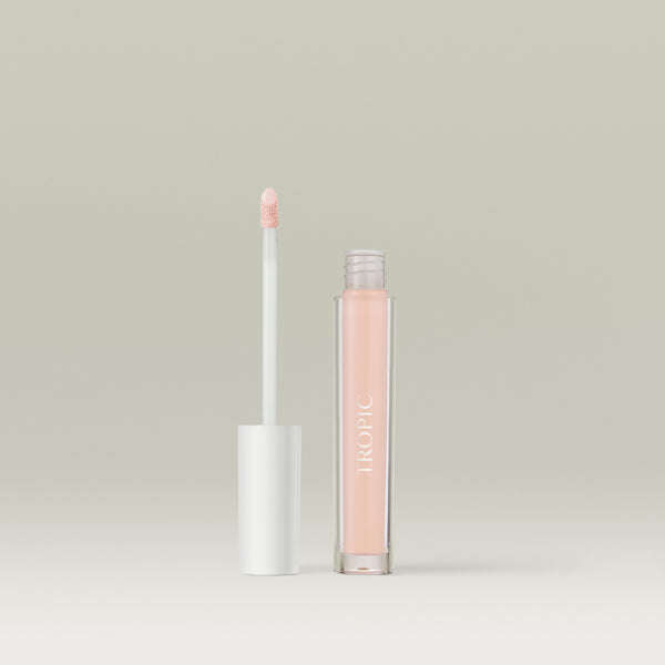 Open tube of Tropic Lip Glaze with the applicator wand standing beside the transparent gloss bottle against a neutral background. Shade Iced Rose.