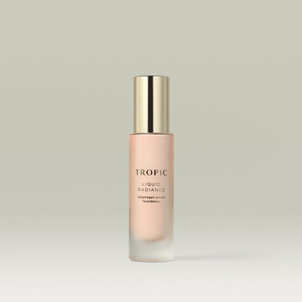 A frosted glass bottle of Tropic Liquid Radiance adaptogen serum foundation in shade 1 with a gold cap, standing upright against a soft neutral background.