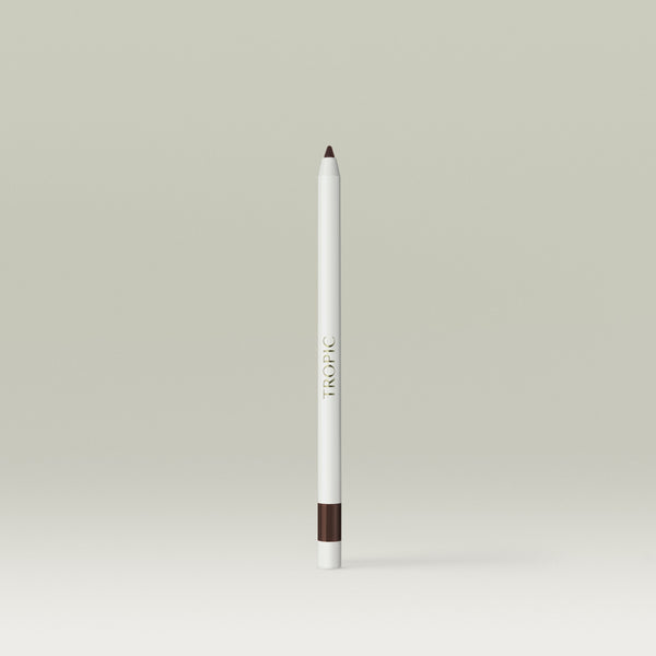 A white pencil-style eyeliner with a deep brown tip and a matching brown band near the base, shown standing upright against a soft, neutral background.