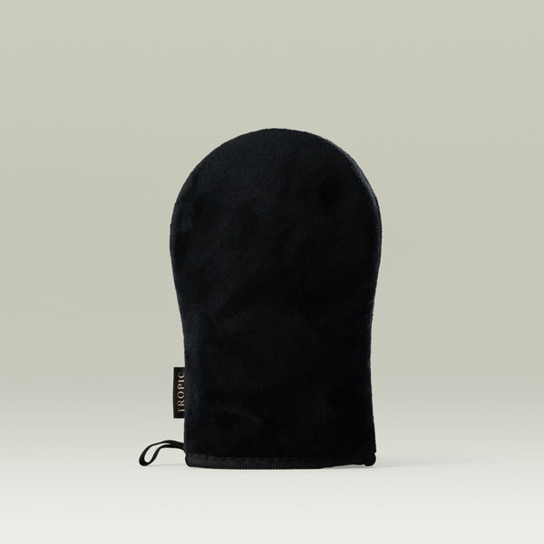 Tropic black tanning mitt with a soft, velvety texture, displayed upright against a neutral background with the Tropic label visible on the side.