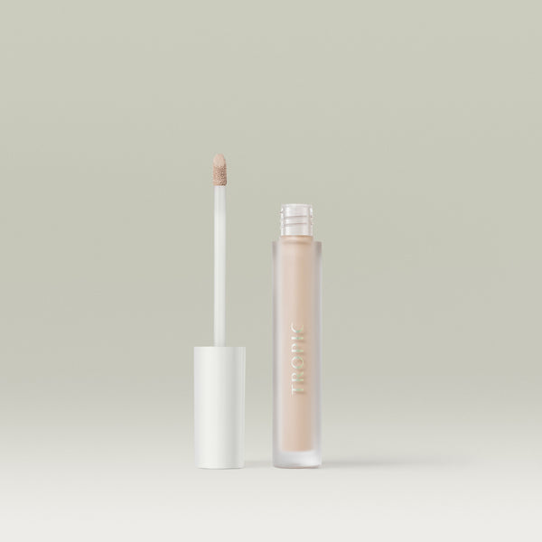 A frosted tube of Tropic Undercover concealer in shade 1 with a white cap, shown open beside its doe-foot applicator coated in product, against a soft neutral background.